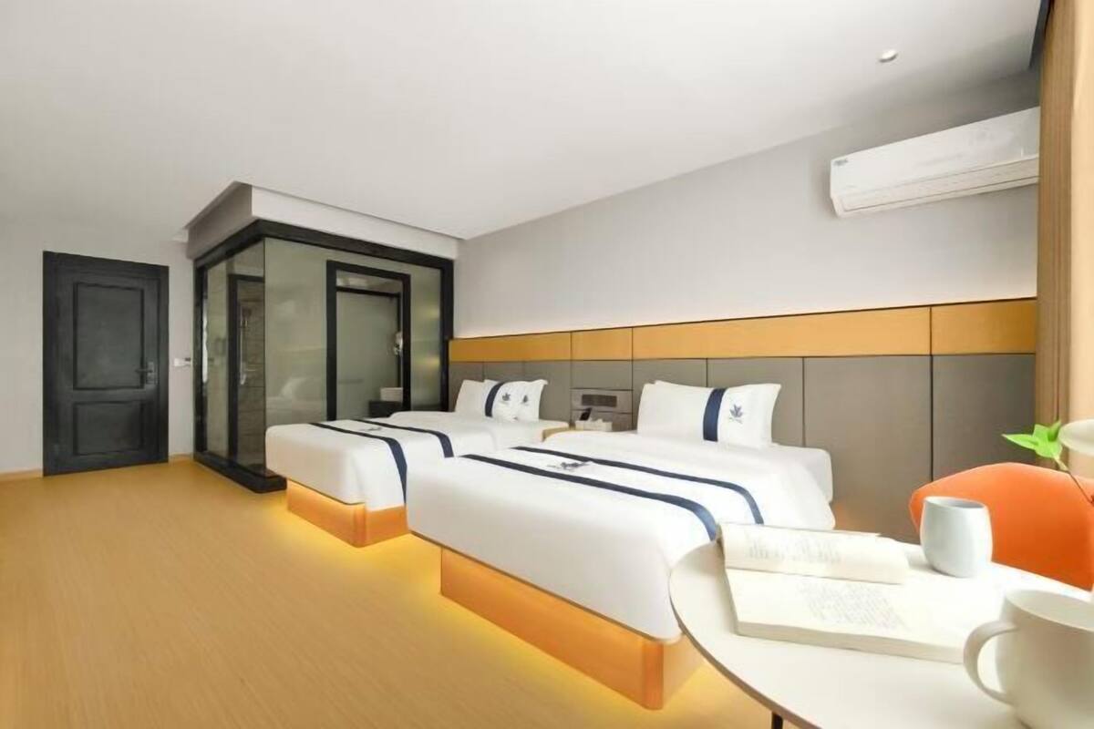 Una habitación de hotel con dos camas, un escritorio, una silla y un equipo de aire acondicionado.