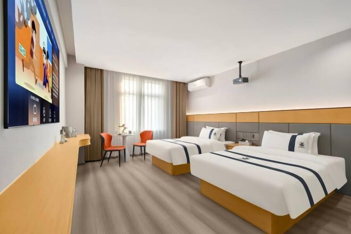 Habitación de hotel con dos camas, un escritorio y una silla.