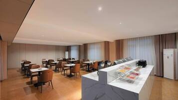 A hotel dining area with a marble counter, multiple tables, and chairs.