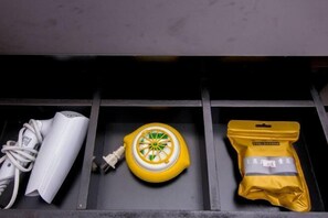 Un cajón con un dispositivo electrónico blanco, un objeto amarillo circular y un paquete amarillo.