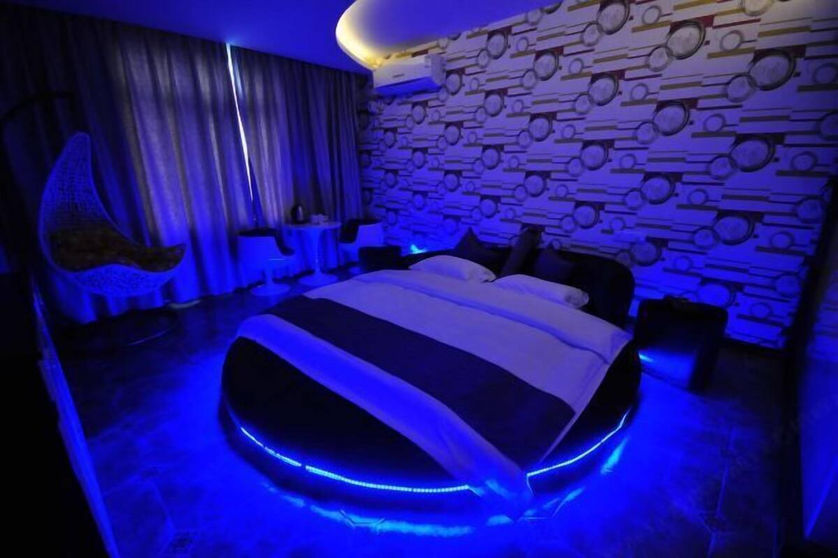 Un dormitorio moderno con una cama redonda, un papel tapiz estampado y un sillón colgante.