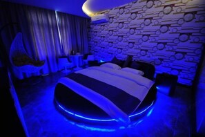 Un dormitorio moderno con una cama redonda, un papel tapiz estampado y un sillón colgante.