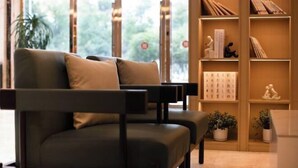 Un soggiorno moderno con un divano, una libreria e vista su spazi verdi.