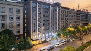 Un hotel moderno a più piani, con un ingresso ben visibile caratterizzato da insegne illuminate e un'area parcheggio antistante.
