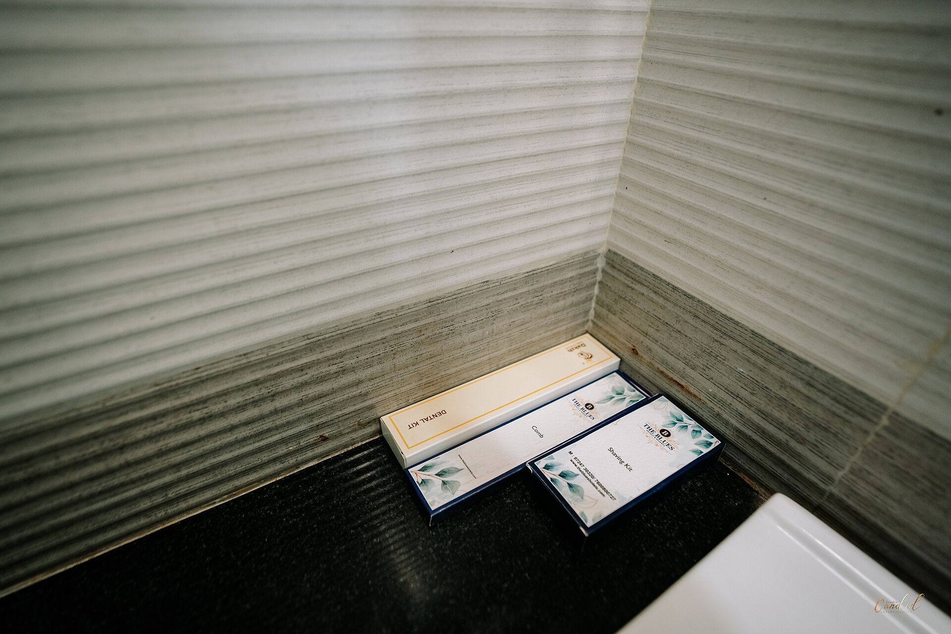 Una esquina de una habitación con pared texturizada y suelo negro. Hay tres cajas en el suelo, una de ellas con la etiqueta 'DENNA'.