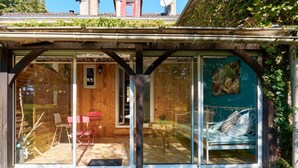 A modern house with a glass conservatory, wooden interior, and a view of the garden.