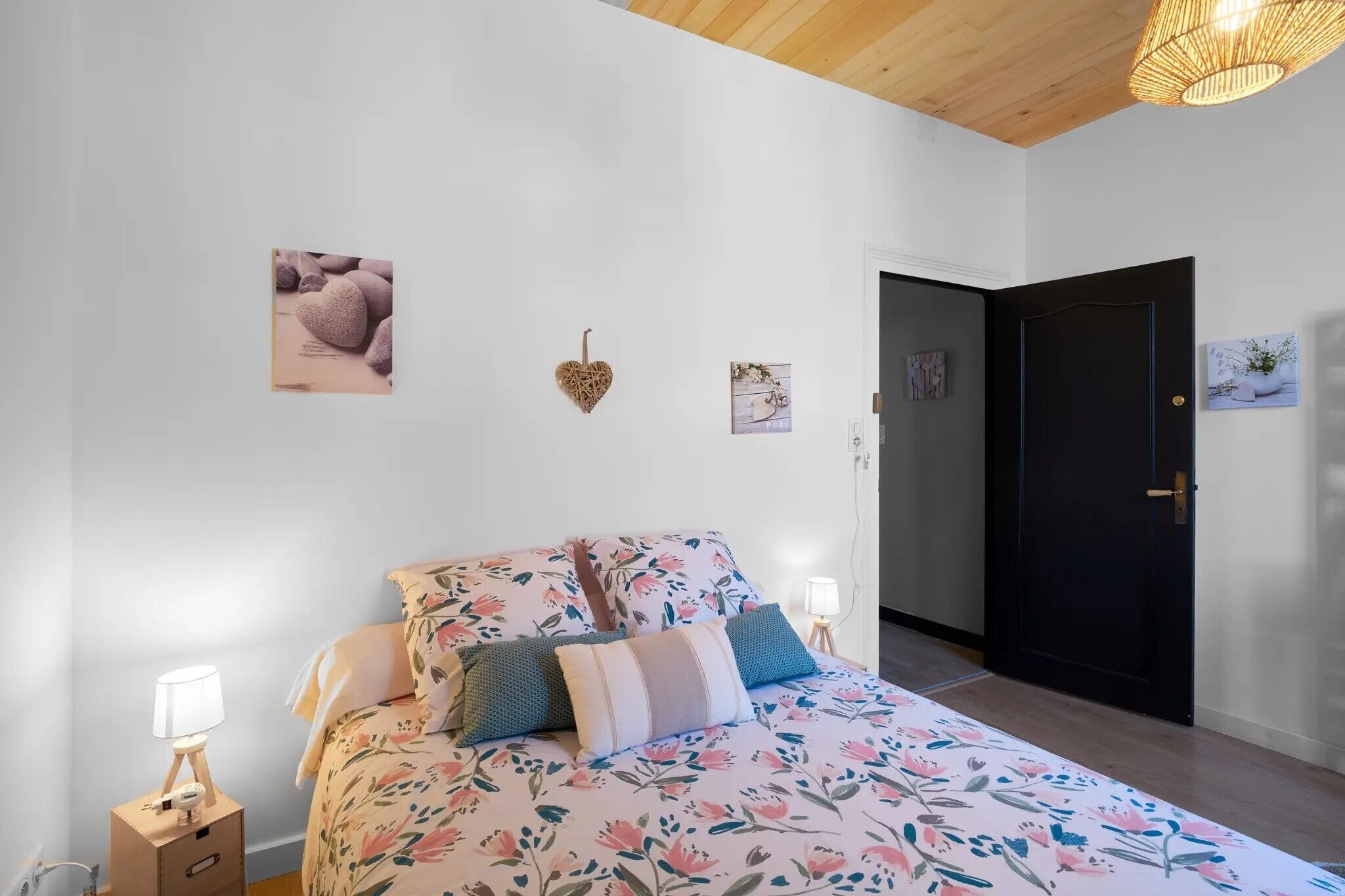A bedroom with a bed, bedside lamps, a door, and wall decorations.