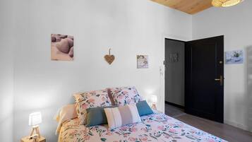 A bedroom with a bed, bedside lamps, a door, and wall decorations.