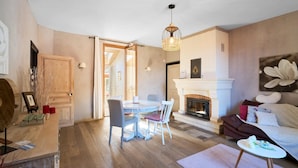A living room with a fireplace, a dining area with a round table and chairs, and a sofa.