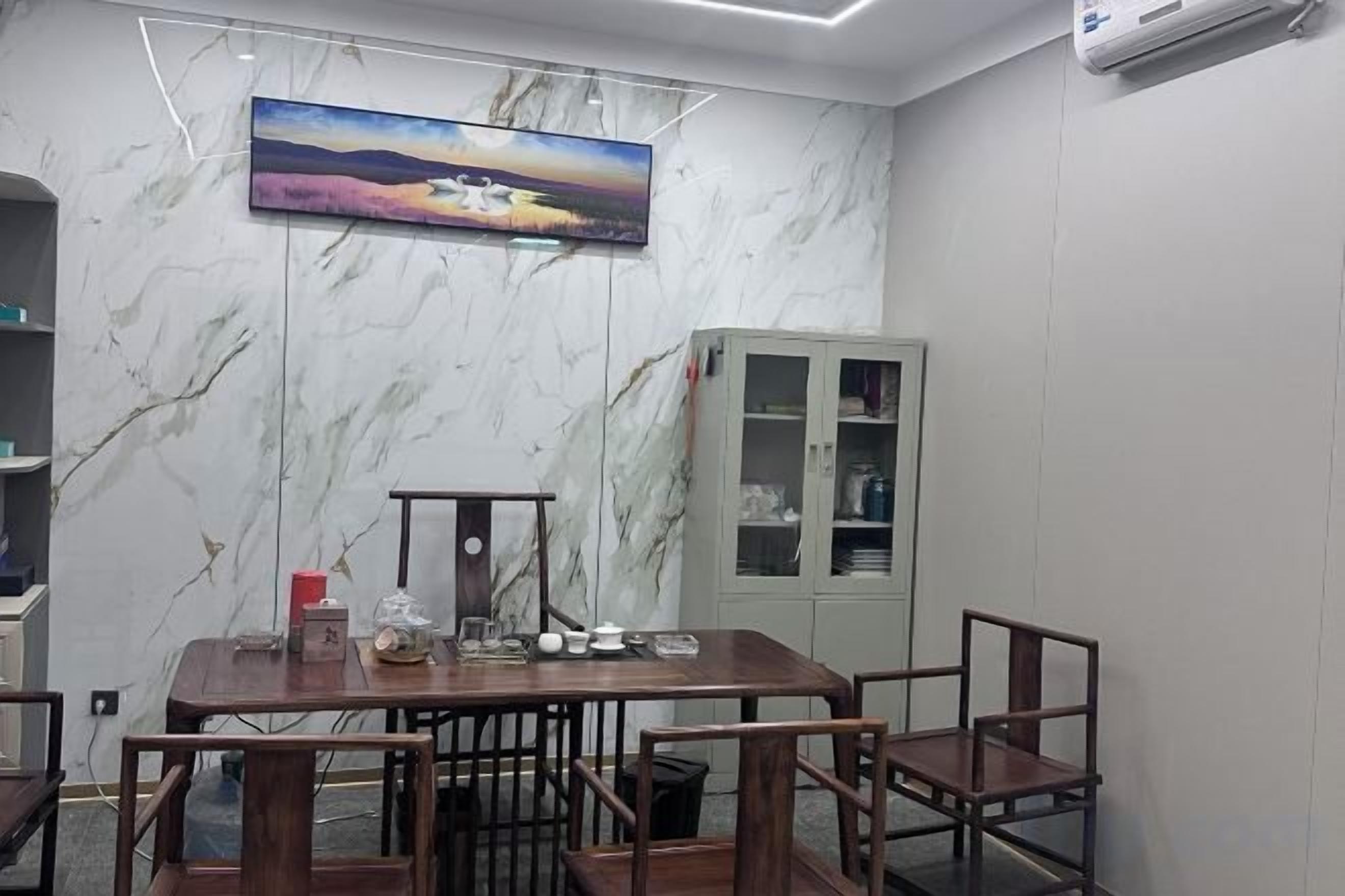 Una sala conferenze con parete in marmo, un quadro, un armadio e un tavolo con sedie.