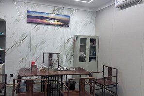 A conference room with a marble wall, a painting, a cabinet, and a table with chairs. - Lingzhi Hotel (Guangzhou)