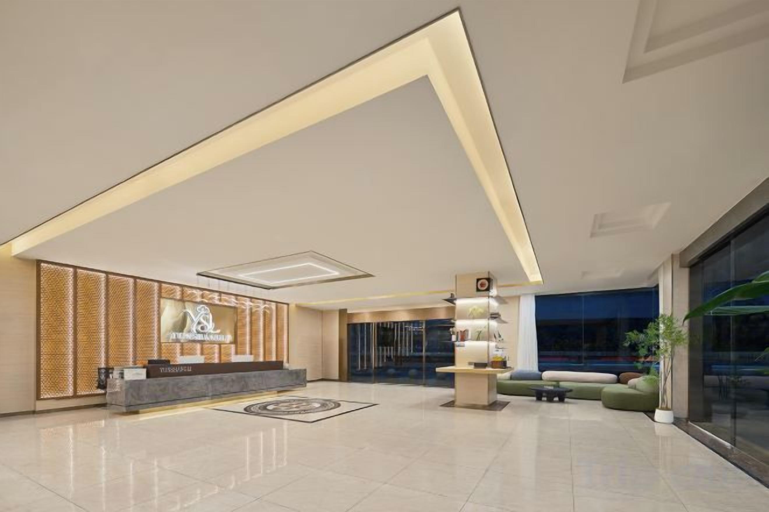 Un vestíbul d'hotel modern amb una recepció, zona de seients i una finestra gran.