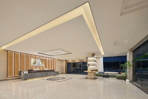 A modern hotel lobby with a reception desk, seating area, and a large window. - Lingzhi Hotel (Guangzhou)