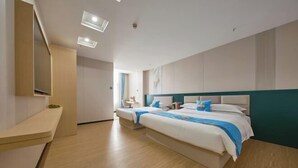 Habitación de hotel con dos camas, un escritorio, un espejo y una ventana.