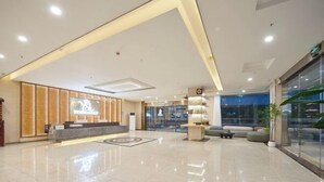 Un moderno vestíbulo de hotel con mostrador de recepción, zona de estar y un amplio escaparate de vidrio.