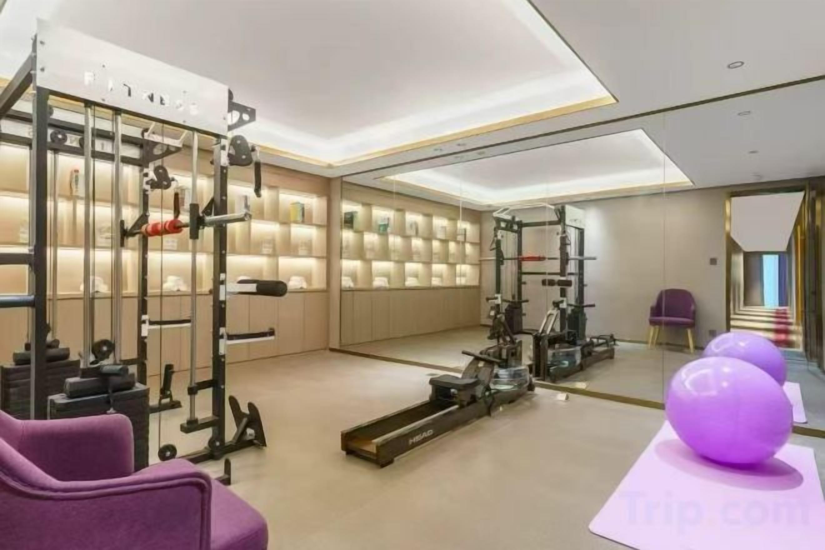 A gym with exercise equipment, a mirrored wall, and a purple exercise ball.