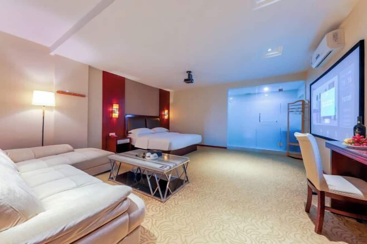 A hotel room with a sofa, a bed, a desk, and a television.