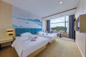 Ein Hotelzimmer mit zwei Betten, einem großen Fenster mit Blick und einem Wandgemälde.