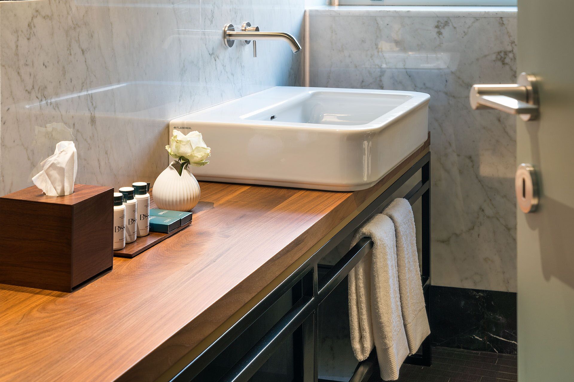 A bathroom with a marble sink, wooden countertop, and a towel rack.