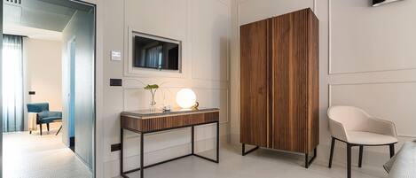 Una habitación de hotel moderna con un muro decorativo de madera, un televisor de pantalla plana, una mesita de noche con lámpara y una silla blanca.
