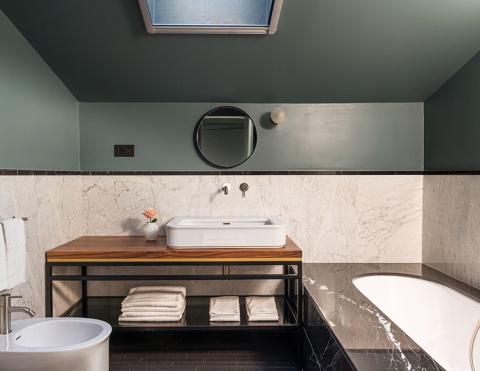 Ein modernes Badezimmer mit Marmorwaschtisch, Waschbecken, Spiegel und Badewanne.