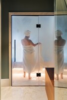 Una habitación con paredes de cristal, puerta corrediza, banca de madera y suelo de baldosas.