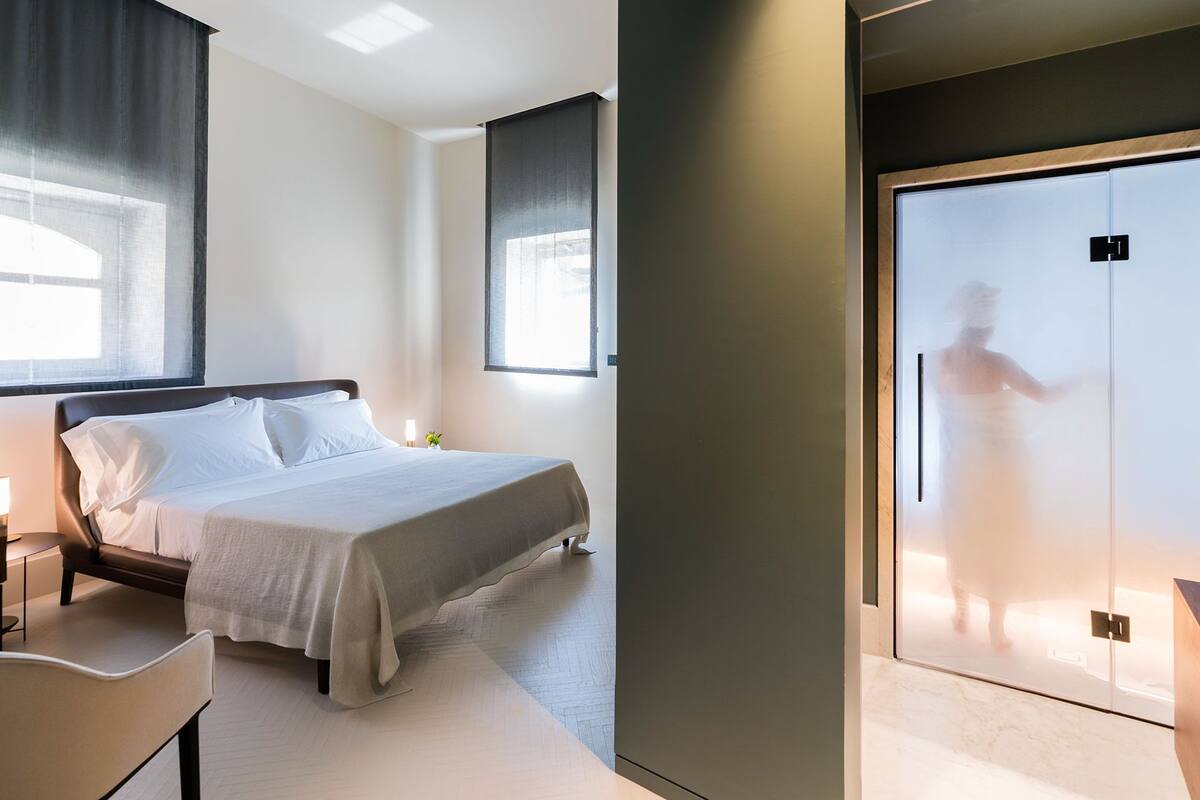 Une chambre d’hôtel moderne, équipée d’un lit, d’une table de chevet et d’une grande armoire.