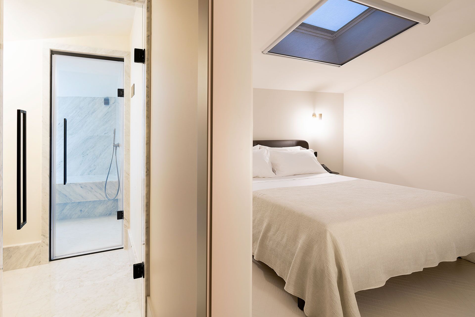 Ein Schlafzimmer mit Oberlicht, einem Bett und einem Badezimmer mit Dusche.