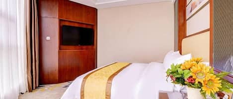 A hotel room with a bed, a television, a vase with flowers, and a wooden headboard.