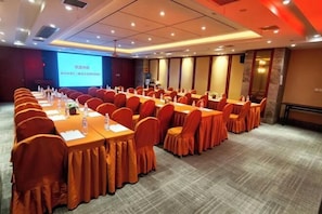 A conference room with long tables and chairs, a projector screen, and a carpeted floor. - Vienna Hotel (Nanchang County Chengbi Lake) (Nanchang)