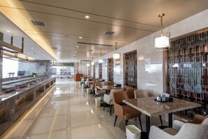 A modern restaurant with a long counter, multiple tables, and a decorative wall.