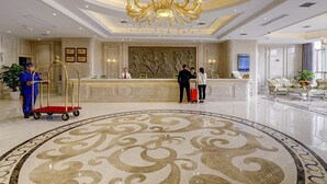 A hotel lobby with a grand chandelier, a reception desk, and a decorative floor pattern. - Vienna Hotel (Nanchang County Chengbi Lake) (Nanchang)