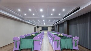 A conference room with rows of purple chairs and green tablecloths, equipped with ceiling lights and a projector screen. - Shiwai Taoyuan Eco Hotel (Huaihua)