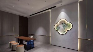 A modern interior with a central table, seating, and a wall-mounted light fixture. - Shiwai Taoyuan Eco Hotel (Huaihua)
