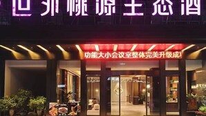 A hotel entrance with a neon sign, a red banner, and potted plants outside. - Shiwai Taoyuan Eco Hotel (Huaihua)
