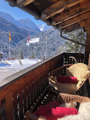 Ein hölzerner Balkon mit Blick auf schneebedeckte Berge und Flaggen.