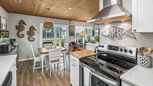 Een moderne keuken met een houten plafond, witte kasten, een groot fornuis en decoratieve vissen aan de muur.