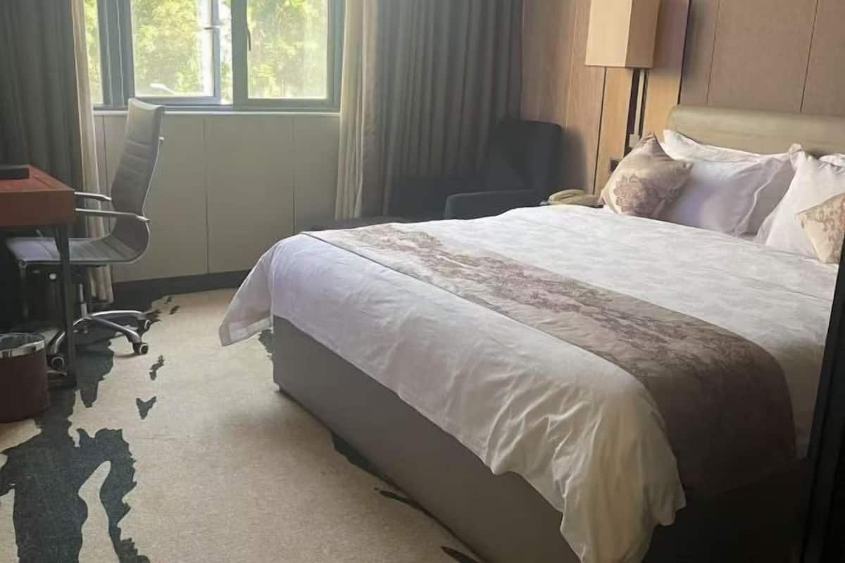 Una habitación de hotel con cama, escritorio, silla y ventana.