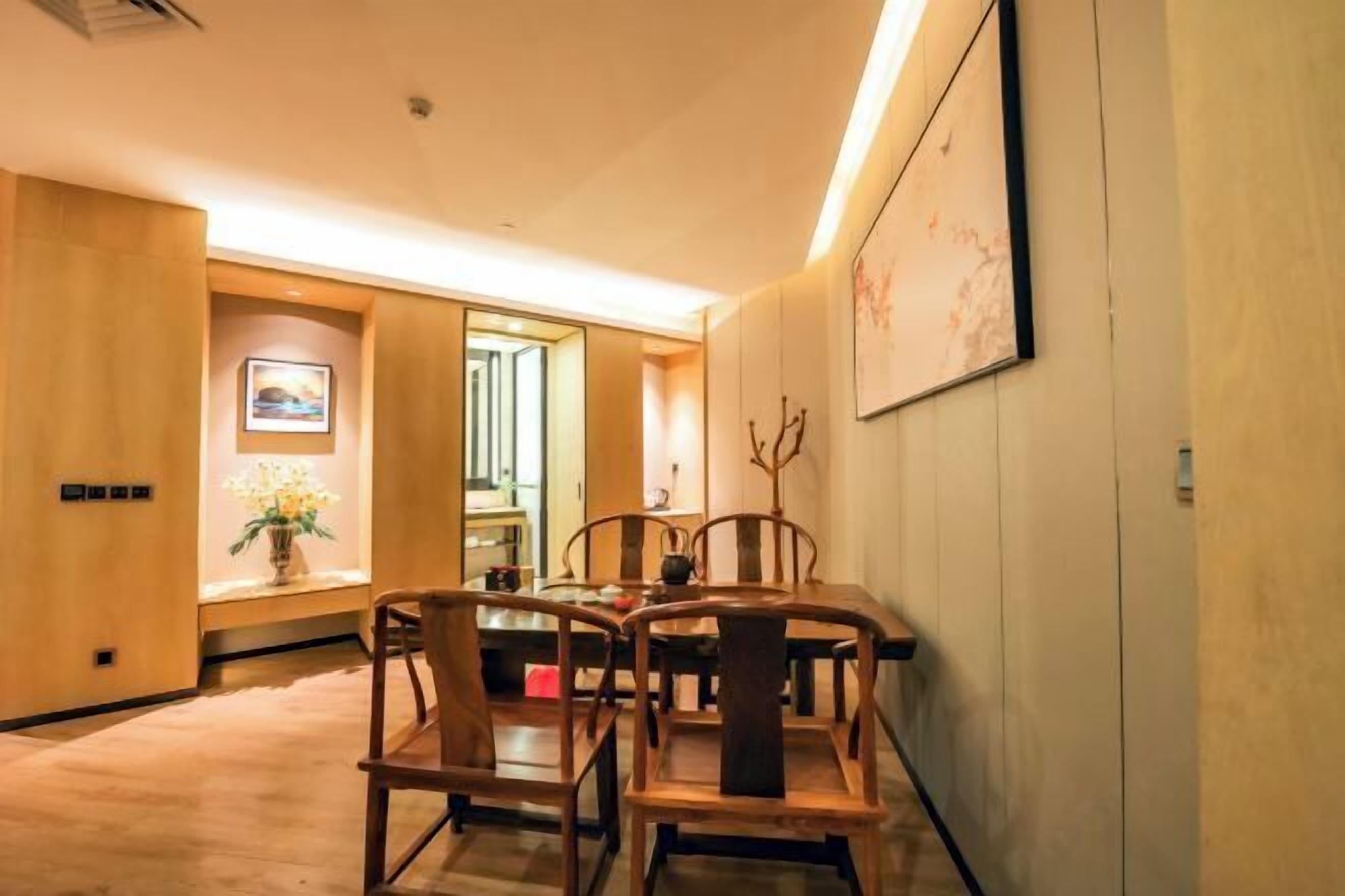 A dining area with wooden furniture, a vase with flowers, and a painting on the wall.
