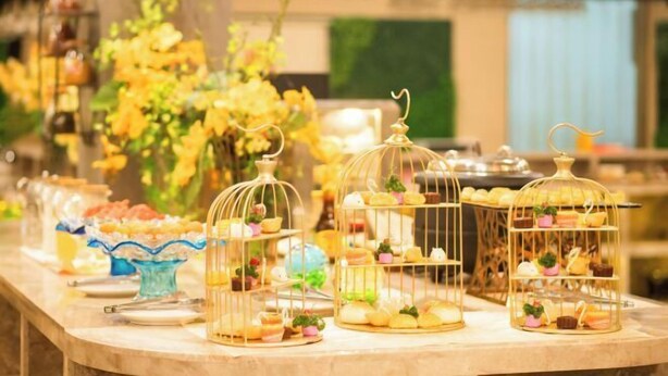A buffet table with various food items displayed in glass containers and on tiered stands. - Garden Hotel (Jiangmen)