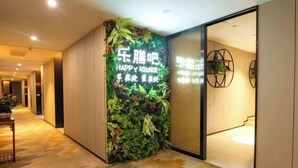 A hallway with a vertical garden wall and a sign that reads "HAPPY LOUNGE". - Garden Hotel (Jiangmen)