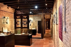 A hallway with brick walls, glass display cases, and a patterned wall divider. - Garden Hotel (Jiangmen)