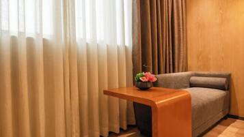 A room with a sofa, a wooden side table, and a vase with flowers.