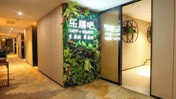 A hotel corridor with a green wall featuring a sign, a wooden floor, and a door leading to a room.