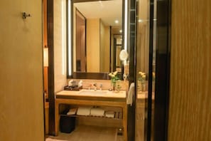 A modern bathroom with a wooden vanity, a large mirror, and a glass shower enclosure. - Garden Hotel (Jiangmen)