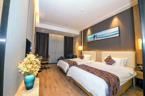 A hotel room with two beds, a desk, a chair, a vase of flowers, and a painting on the wall. - Garden Hotel (Jiangmen)