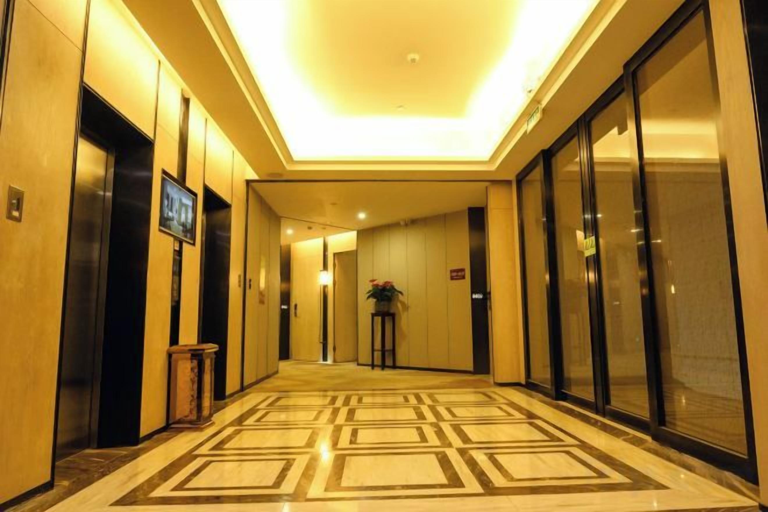 A hotel corridor with elevators, a television, and a patterned floor.
