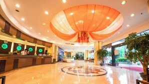 A hotel lobby with a circular seating area, a reception desk, and a large decorative ceiling. - Garden Hotel (Jiangmen)