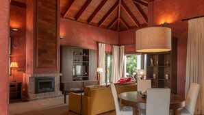 Una sala de estar con chimenea, sofá, mesa de comedor y una lámpara grande.
