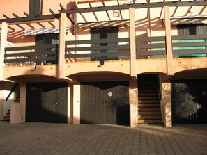 Een gebouw met meerdere garagepoorten, een trap en een overdekte doorgang.